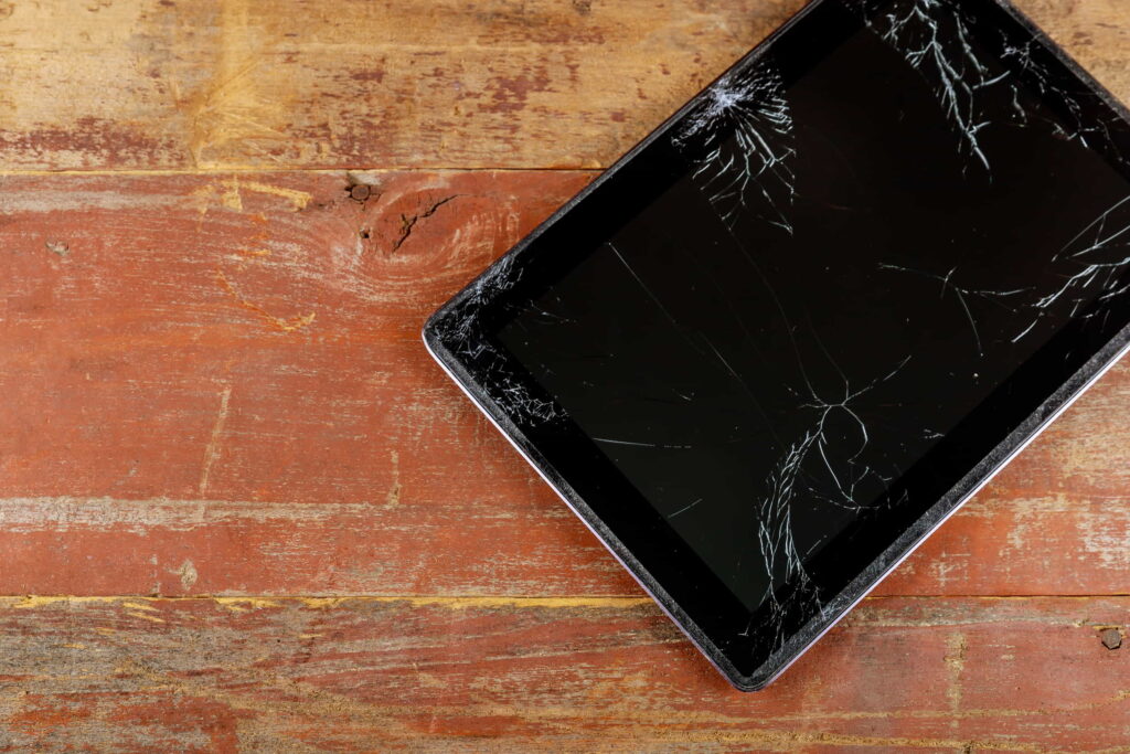 A tablet with a cracked screen on a wooden background