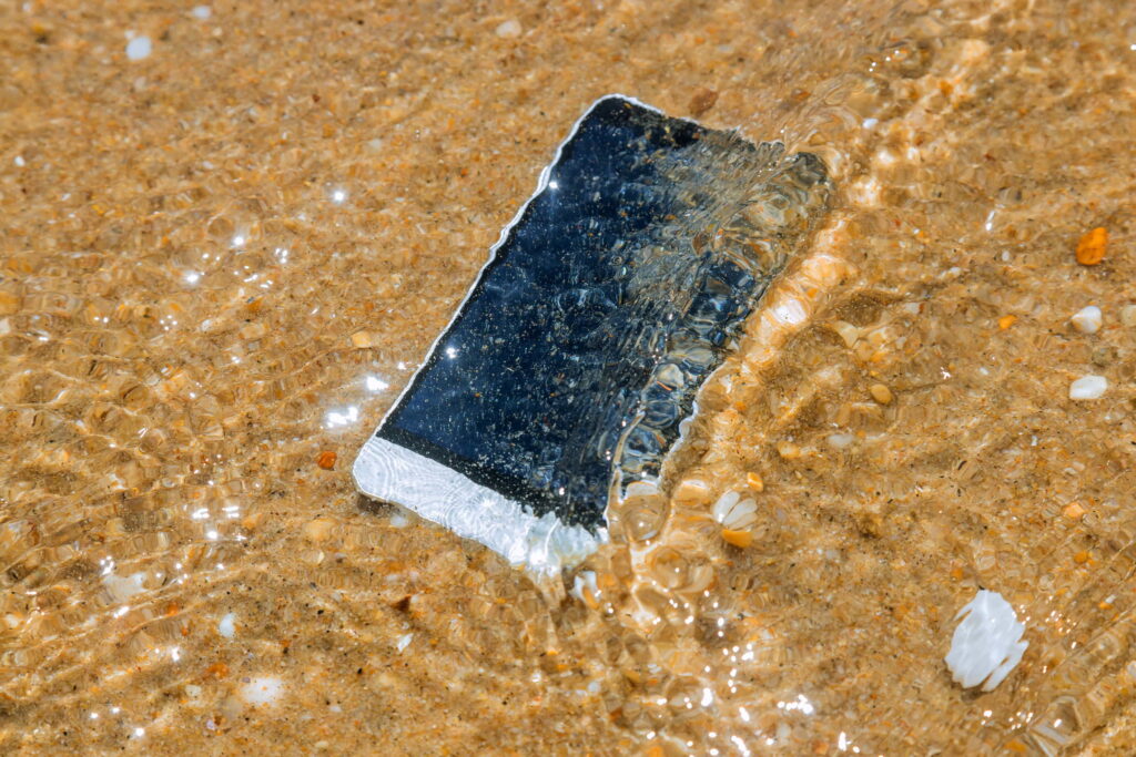 A smartphone submerged in water on the beach
